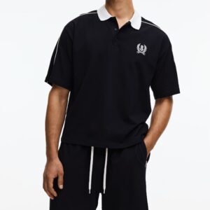 Un ensemble 2 PIÈCES SLOW DOWN, chemise noire à manches courtes et de short assorti est présenté de profil. La chemise est ornée de passepoils blancs le long des coutures des épaules et descendant le long des manches, tandis que le short est doté de passepoils blancs courant verticalement de chaque côté